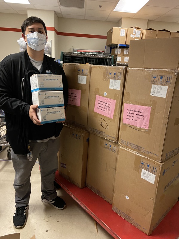 A man holding boxes of N95 masks. 