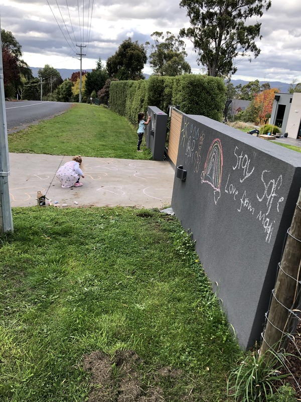Children writing chalk messages in a driveway.