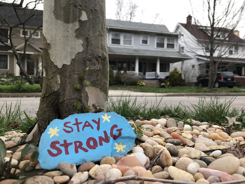 A rock against a tree that says "Stay Strong".