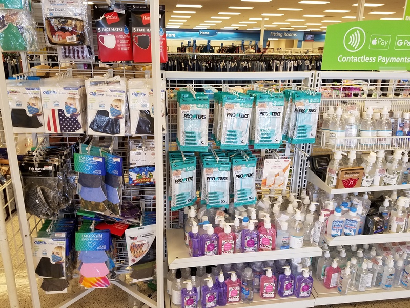 This is a picture of a shelf full of COVID-19 prevention products at a store, including face masks, sanitizing wipes, and hand sanitizer. 