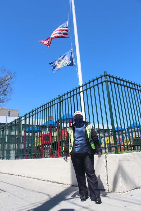 A person standing in front of a playground and a flagpole. 