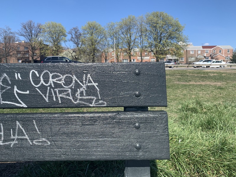 white graffiti on a black bench saying "corona virus"