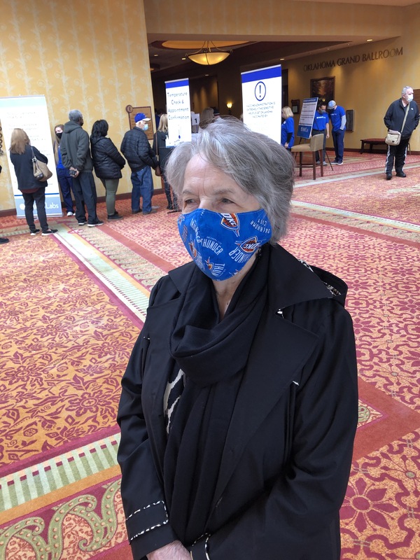 Masked older woman in line for a COVID-19 vaccine.
