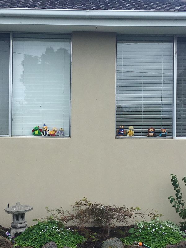 Stuffed animals sitting on the window. 