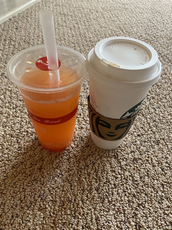This is a picture of an orange drink set next to a Starbucks coffee cup. 