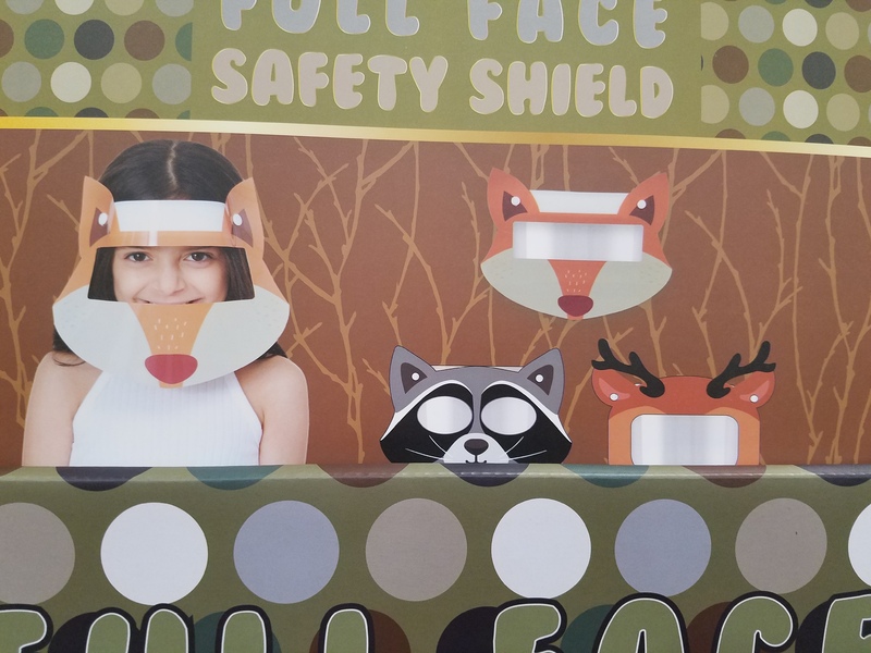 This is a picture taken of a wall, where a person can place their eyes behind pictures of various animals. Next to the animals, the image of a girl looking through a full animal themed face mask can be seen, under the words "Full face safety shield". 