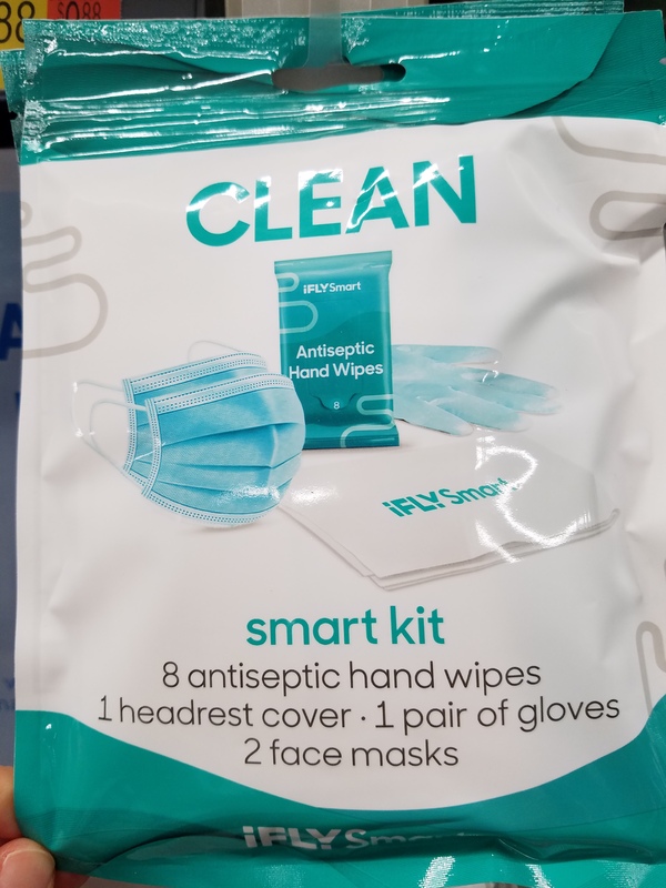 This is a picture of a turquoise package of items relating to COVID-19 protection. A pair of gloves, a face mask, and a wipe reading 'iFlySmart' decorate the front of the package. Text reading "Smart Kit: 8 antiseptic hand wipes, 1 headrest cover, 1 pair of gloves, and 2 face masks" appears on the package. 