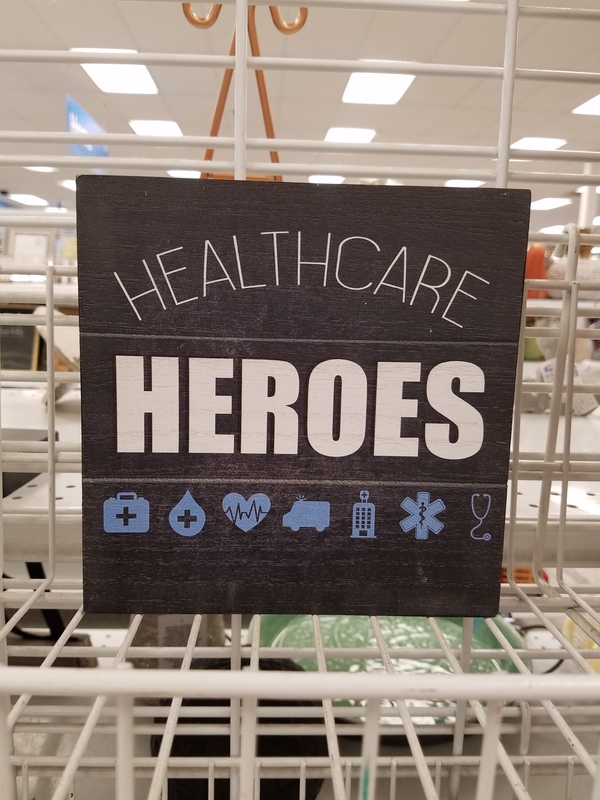 This is a picture of a black sign which reads "Healthcare Heroes". Several symbols related to medical workers are shown below the sign. 