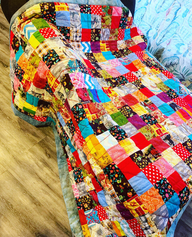 This is a picture of a large, multicolored quilt that a person created during the COVID-19 Pandemic lock down. 
