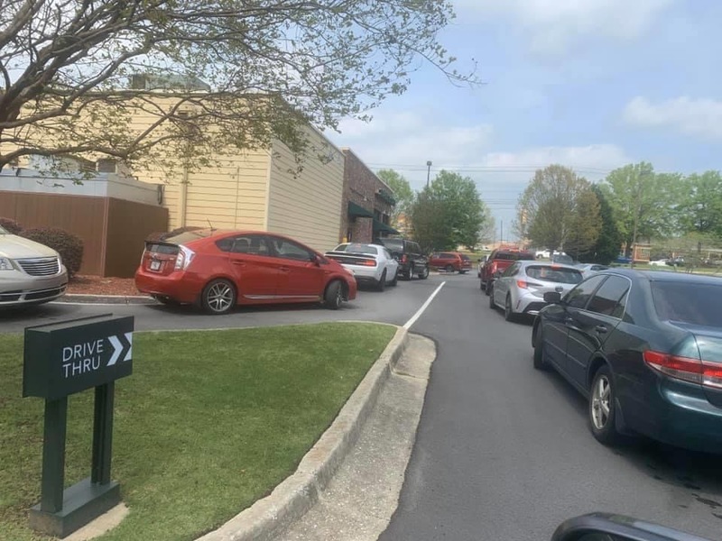 A long line of cars next to a building. 