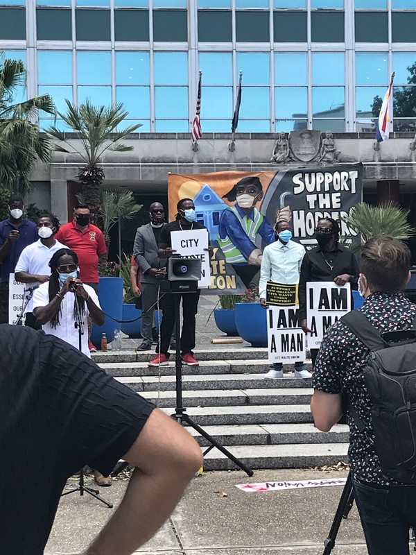 Image of people gathered, wearing masks, in front of city hall in New Orleans for the Solidarity Conference.