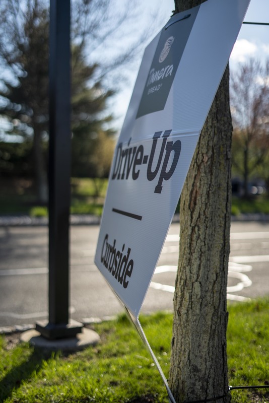 A sign by the restaurant Panera that says "Drive-up/Curbside."