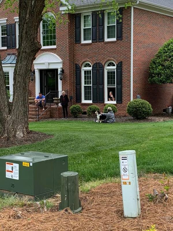 Four people talking outside of a house. 