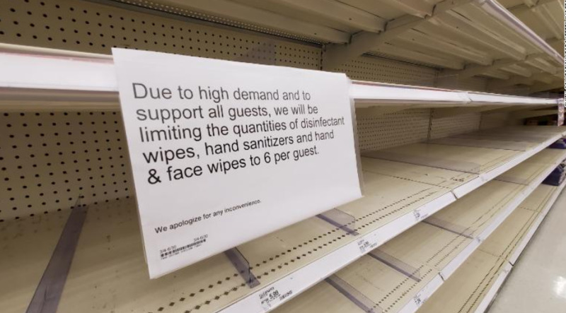A sign on a store shelf reading "Due to high demand and to support all guests, we will be limiting the quantities of disinfectant wipes, hand sanitizer and hand and face wipes to 6 per guest".