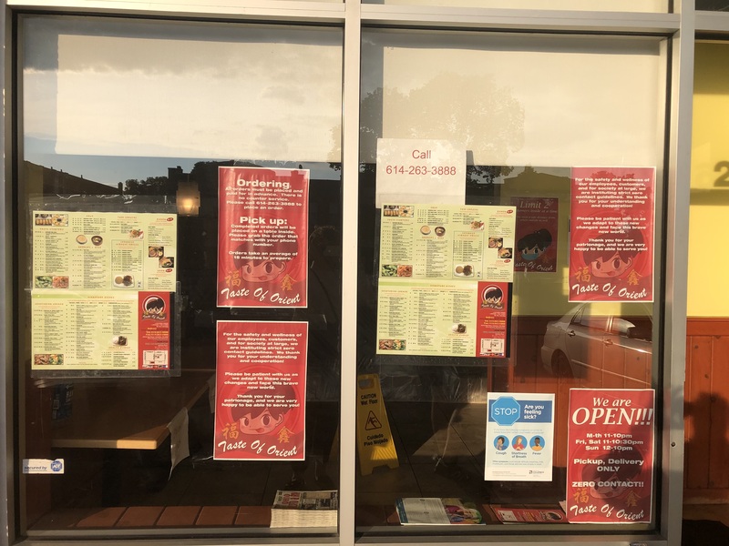 A restaurant window filled with posters of COVID-19 protocols and menus. 