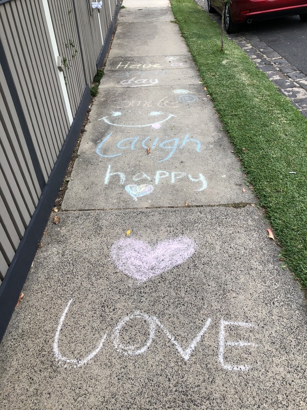 A sidewalk with chalk written on it. 