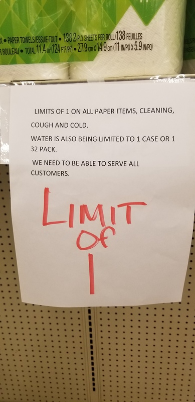 A sign that is taped on a shelf below paper towels. 