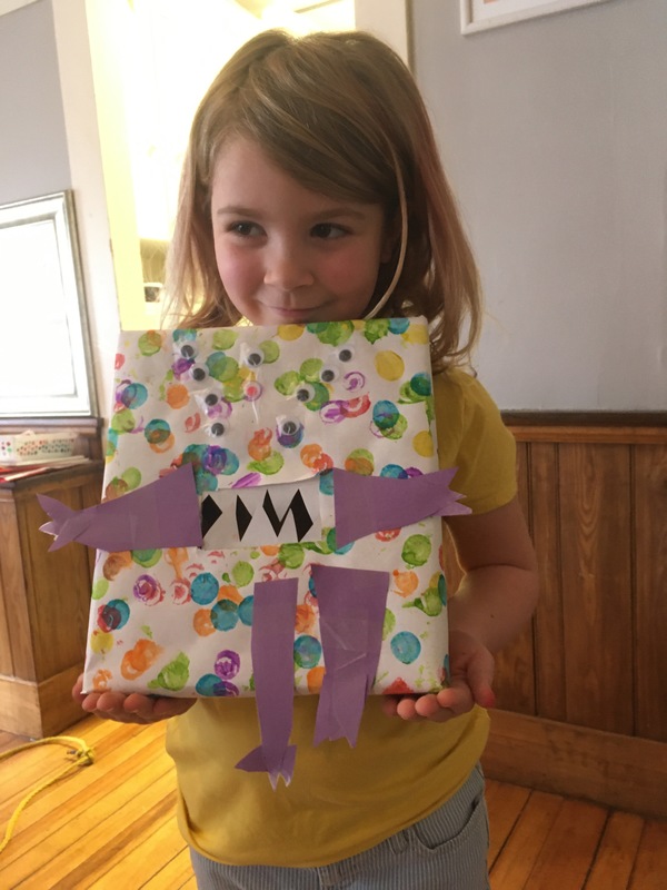 A little girl holding an art project. 