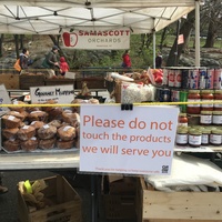 A sign at a farmers market that says "Please do not touch the products we will serve you."