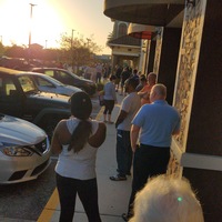 A long line of people are waiting outside of a grocery store. 