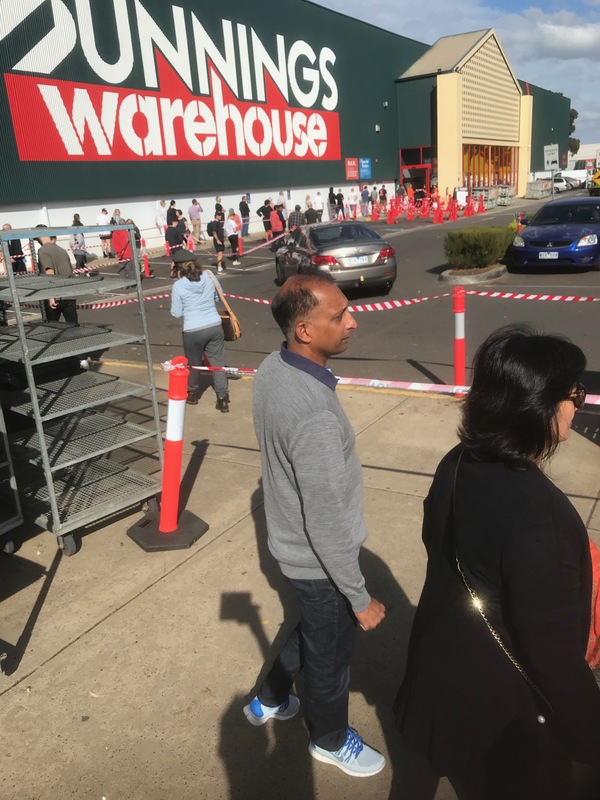 A line of people outside a warehouse.