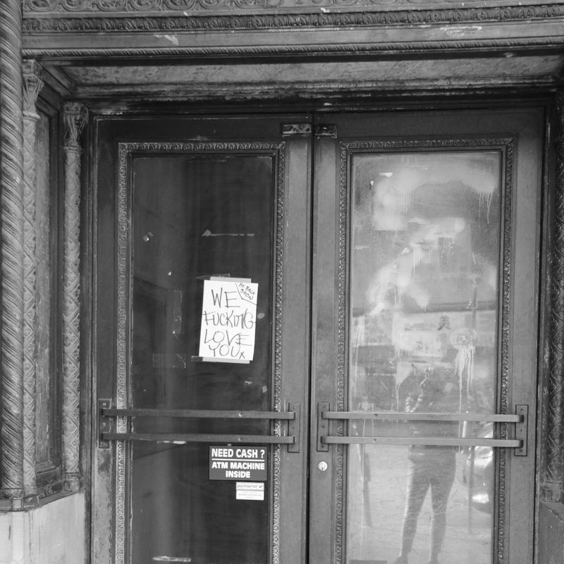 A white flyer posted on closed double doors.