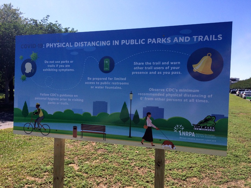 A sign in a park about social distancing.