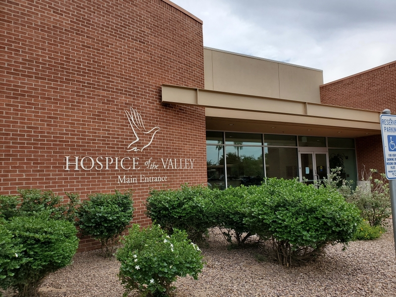 The front of a brick building with plants beside it. 