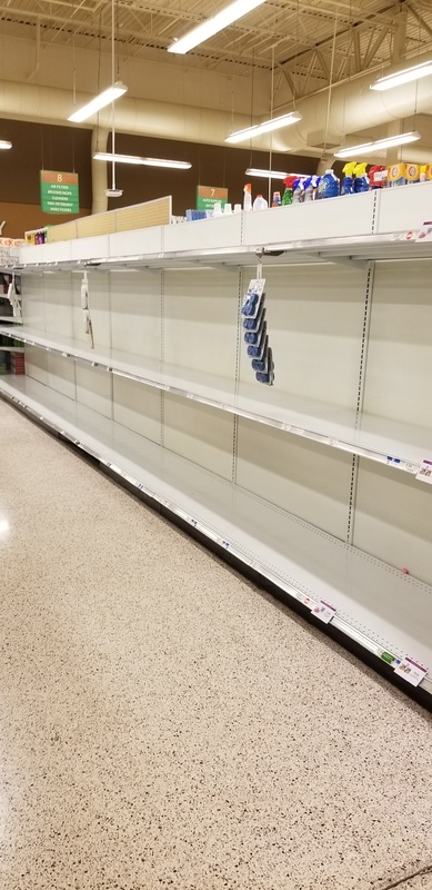 An aisle in a grocery store with empty shelves.