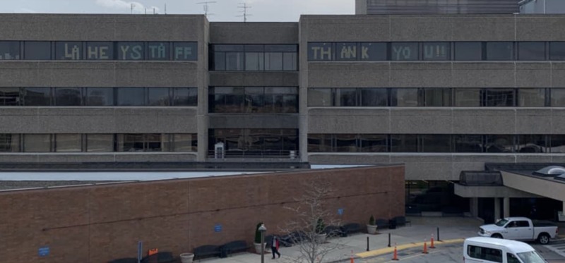 Lahey Hospital and Medical Center with 7 central unit on the top floor in the windows showing the message, "LAHEY STAFF THANK YOU!!"