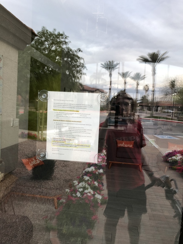 A window to an apartment office with a piece of paper being held up against the inside of the window that is informing tenants about the office closure.