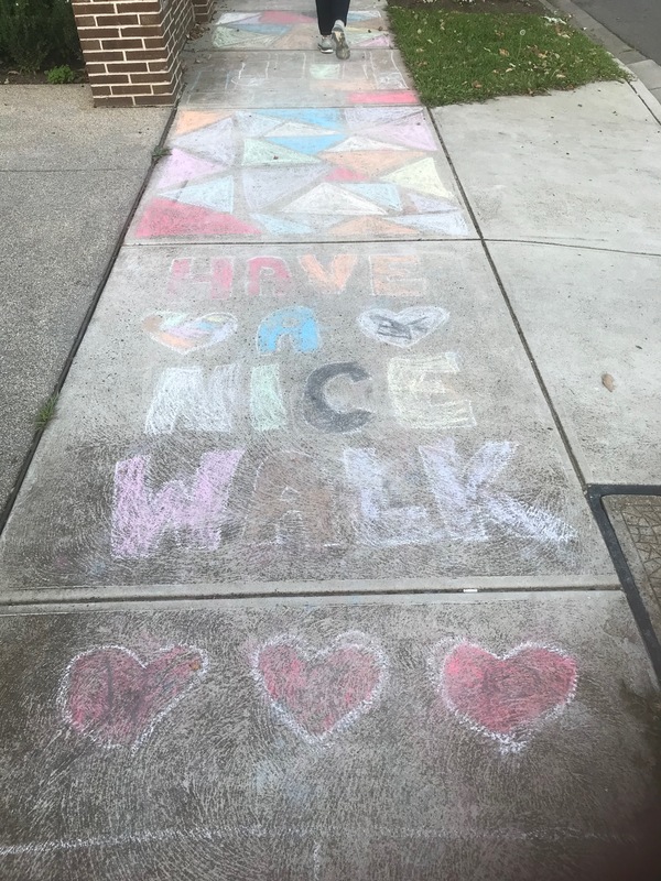 Chalk message on a sidewalk that reads "Have a nice walk".