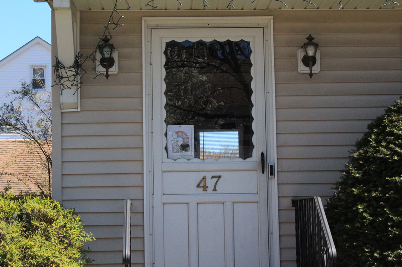 Residential house with a rainbow on the front screen door.