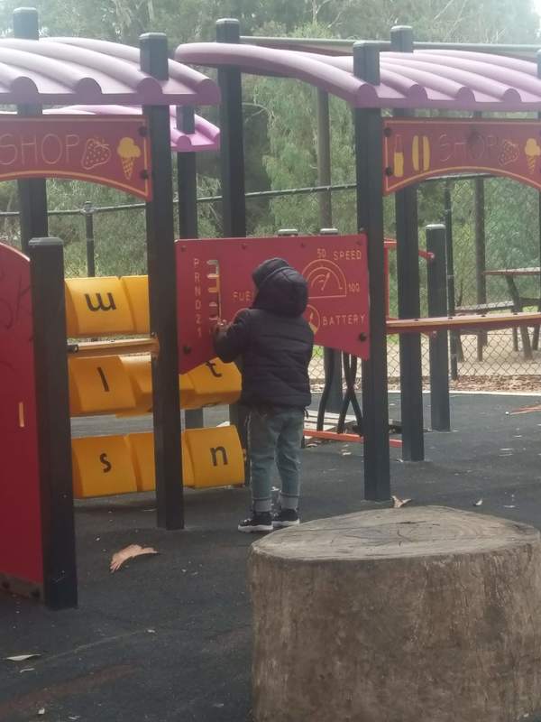 A child in a black puffer coat is playing on a playground.