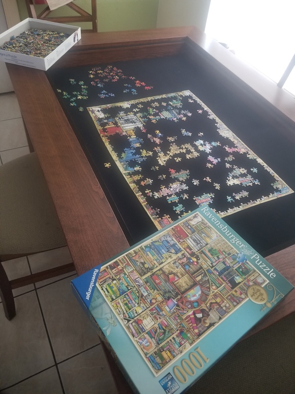 A table that has a puzzle being put together in progress.