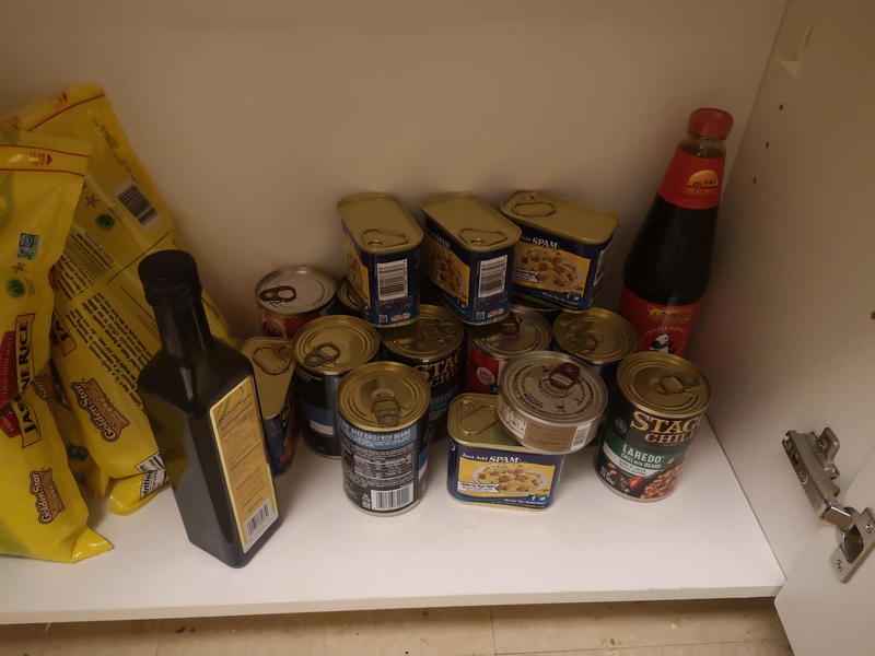 A shelf with multiple cans of food.