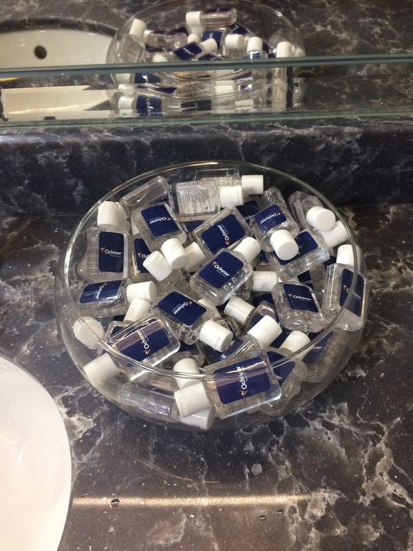 A glass bowl full of travel size hand sanitizer bottles.