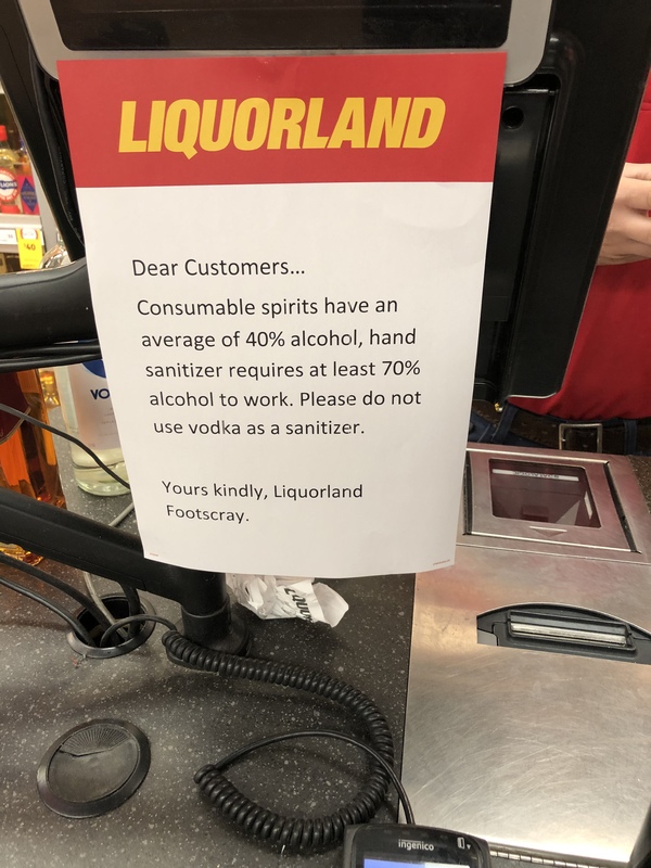 A paper sign taped on the front a register says: Dear Customers... Consumable spirits have an average of 40% alcohol, hand sanitizer requires at least 70% alcohol to work. Please do not use vodka as a sanitizer. Yours kindly, Liquorland Footscray.
