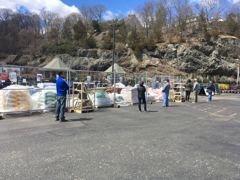 People with masks waiting in line outside of a gated center.