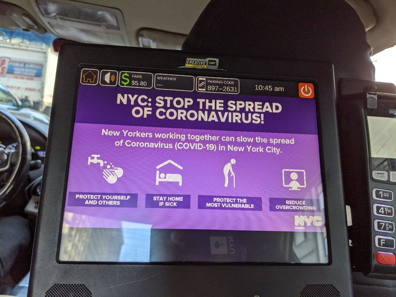 A tablet on the back of a passenger seat in a taxi that says: NYC: STOP THE SPREAD OF CORONAVIRUS! New Yorkers working together can slow the spread of Coronavirus (COVID-19) in New York City. Protect yourself and others, stay home if sick, protect the most vulnerable, reduce overcrowding.