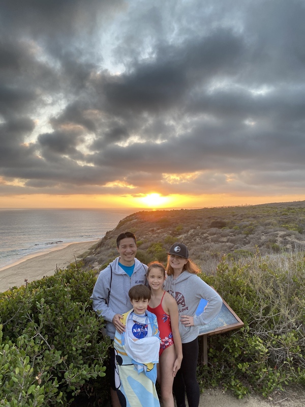 This is a picture of a family of four at the beach during sunset.