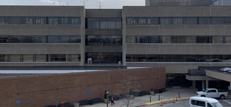 Lahey Hospital and Medical Center with 7 central unit on the top floor in the windows showing the message, "LAHEY STAFF THANK YOU!!"