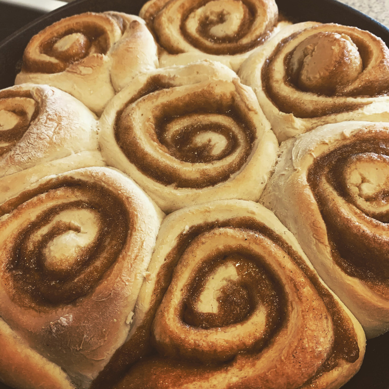 This is a picture of freshly baked cinnamon rolls sitting in a tray.