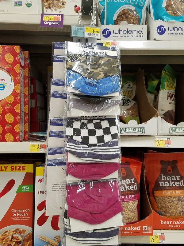 This is a picture of packaged face masks for sale at a store next to other food items on shelves.