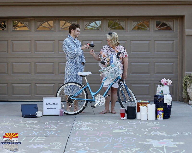 Two people posing behind toiletries and a laptop in front of their garage.