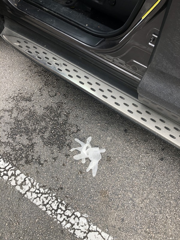 A disposable glove is on the ground in a parking lot.