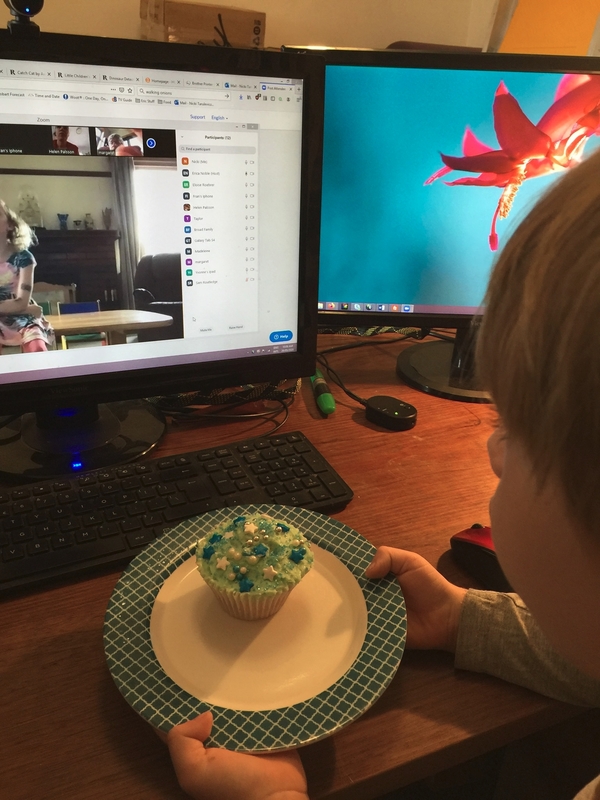 A child having a cupcake to celebrate a birthday party via zoom.