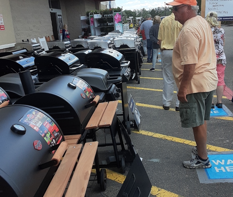 People waiting in line next to grills.