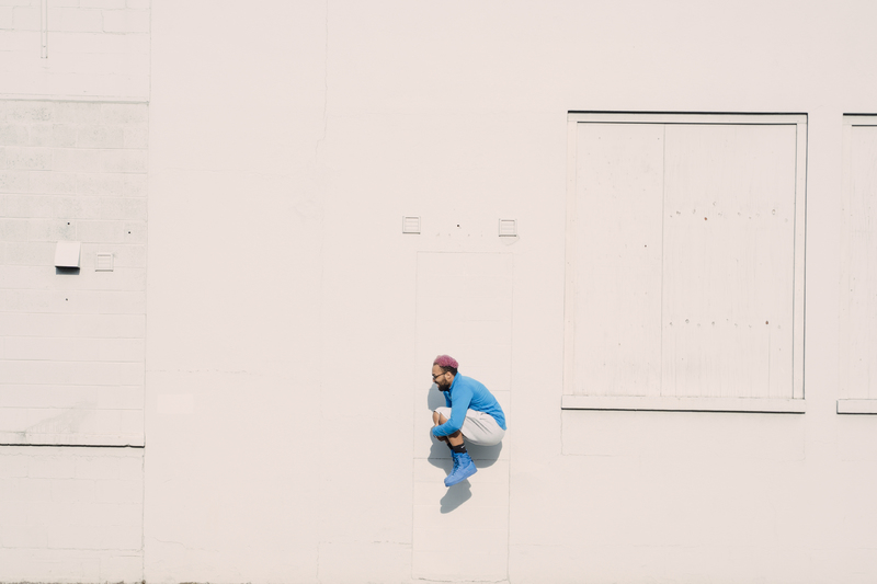 A person curled up in a beige background.