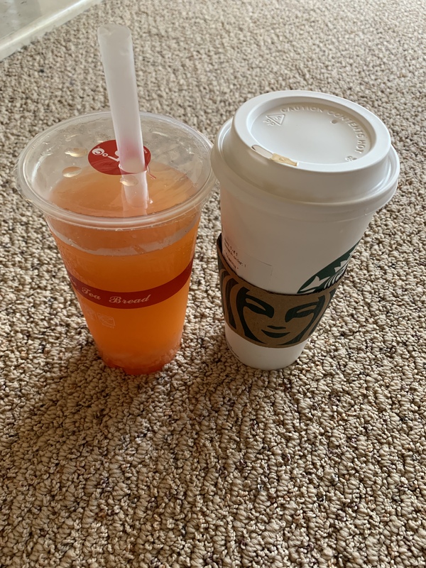 This is a picture of an orange drink set next to a Starbucks coffee cup.
